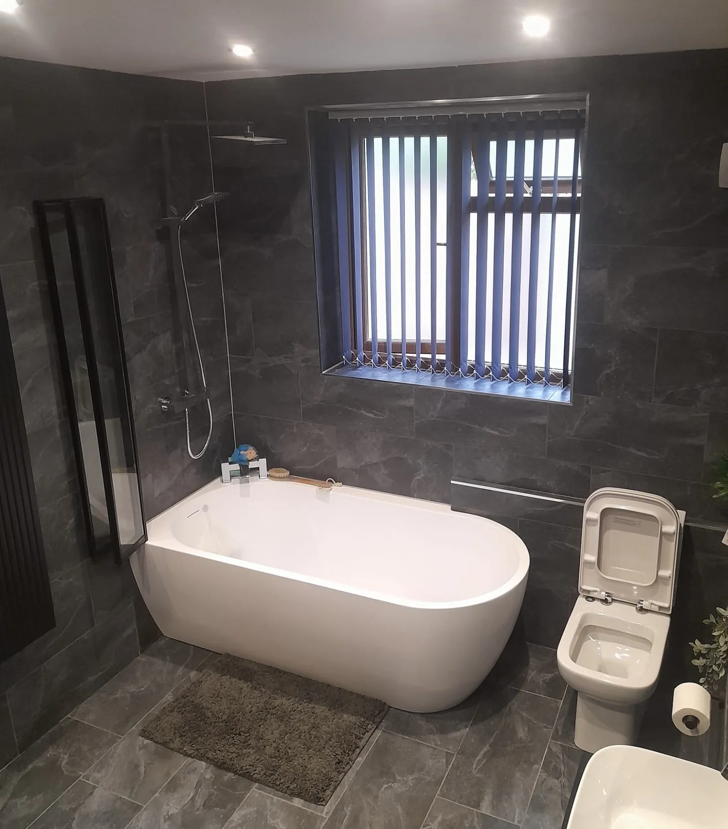 Completed dark tiled bathroom with freestanding bath by Campbell and Sons